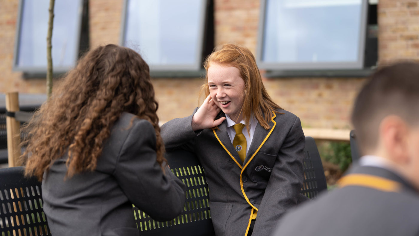 A student talking to another student in a school outside