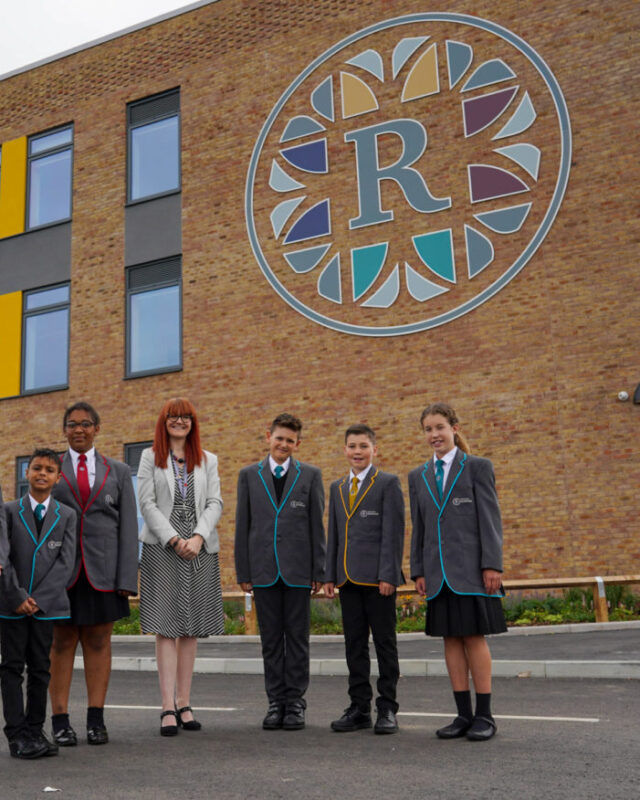 Six Leigh Academy Rainham students are seen posing for a photo outside the academy building, alongside the Principal, Alex Millward.