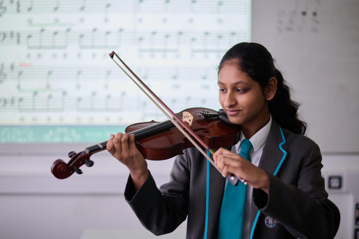 A student in LAR uniform playing the violin