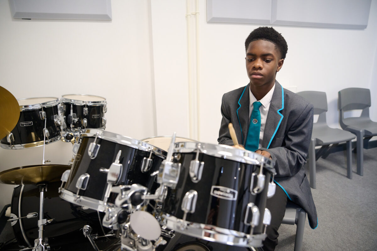 A student playing a black drum kit