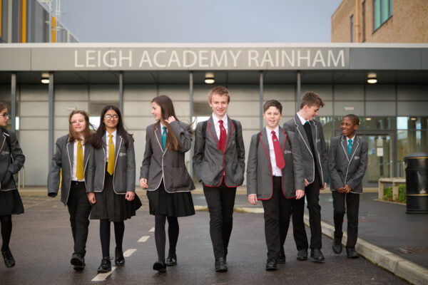 A group of students in LAR uniform, walking towards the camera, with the school building behind them